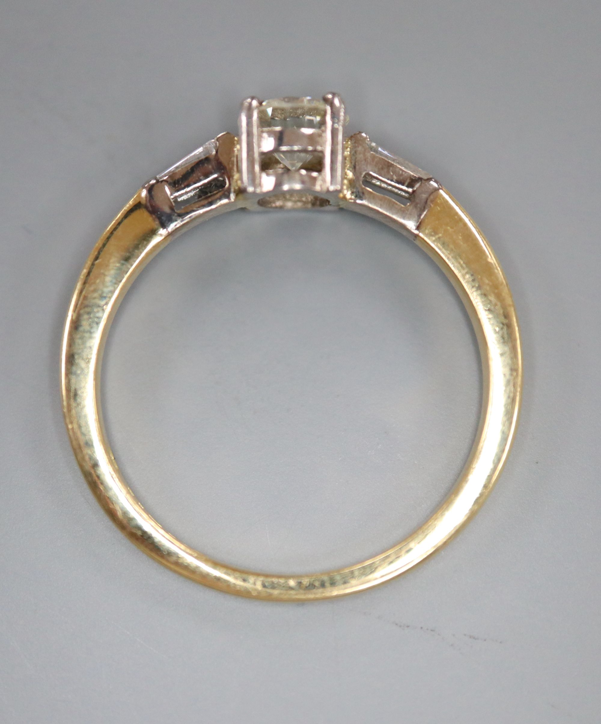 A modern 18ct gold and single stone diamond ring, with trapeze cut diamond set shoulders, size O, gross 3.7 grams,